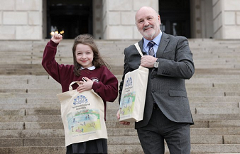 The Speaker, Alex Maskey and the Eco-Bag Competition winner, Ruby Farmer from the Diamond Primary School, in front of Parliament Buildings holding reusable bag with the winning design